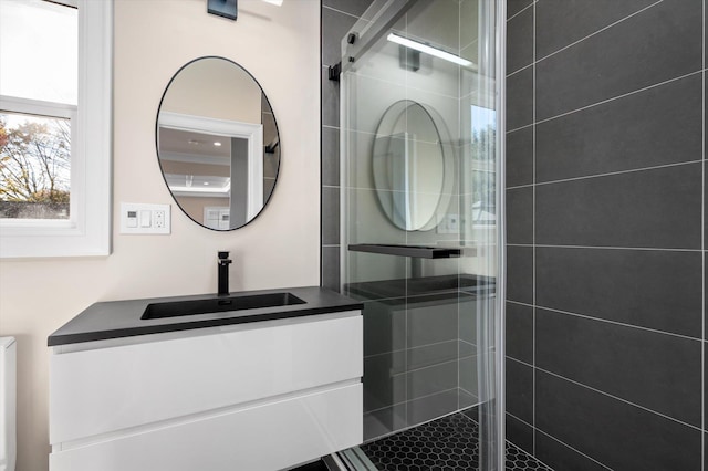 bathroom featuring a shower with door and vanity