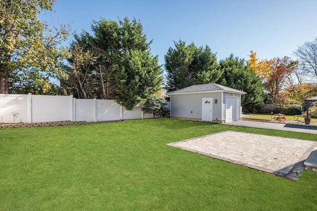 view of yard featuring a garage, a patio area, and an outbuilding