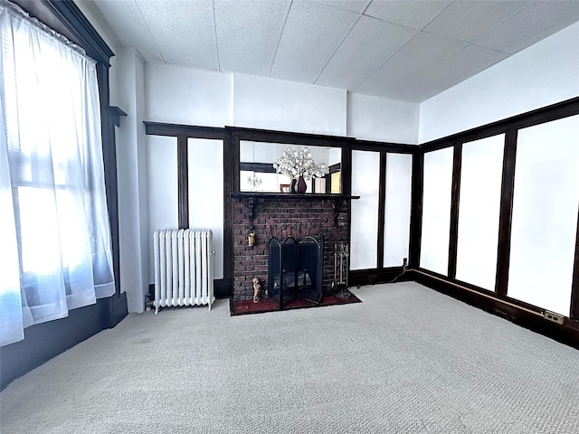 unfurnished living room with radiator, carpet floors, and a fireplace