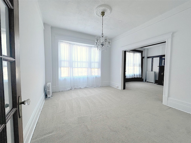 empty room with light colored carpet, radiator heating unit, a chandelier, and a textured ceiling