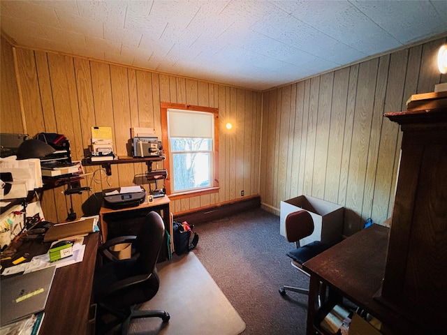 office area with dark colored carpet and wooden walls