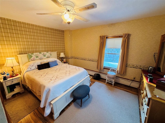 bedroom with ceiling fan, a baseboard heating unit, and dark hardwood / wood-style floors