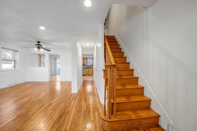 stairs with wood-type flooring and ceiling fan