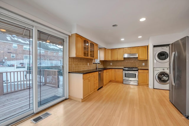 kitchen featuring stacked washer and dryer, sink, appliances with stainless steel finishes, backsplash, and light wood-type flooring