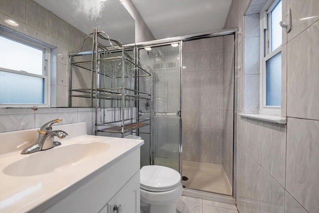 bathroom with vanity, plenty of natural light, tile walls, and toilet