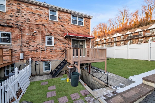 back of property featuring a wooden deck, central AC unit, and a lawn