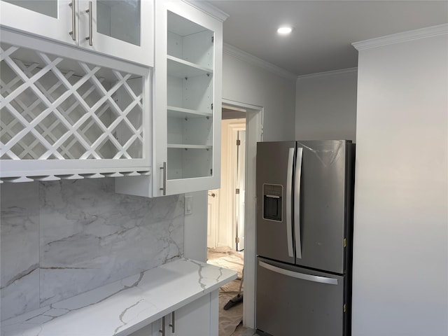 kitchen featuring white cabinetry, backsplash, crown molding, light stone counters, and stainless steel refrigerator with ice dispenser