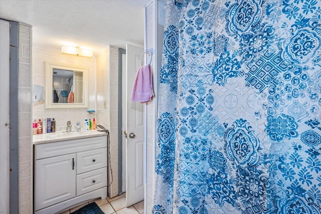 bathroom with walk in shower, tile patterned floors, vanity, and a textured ceiling