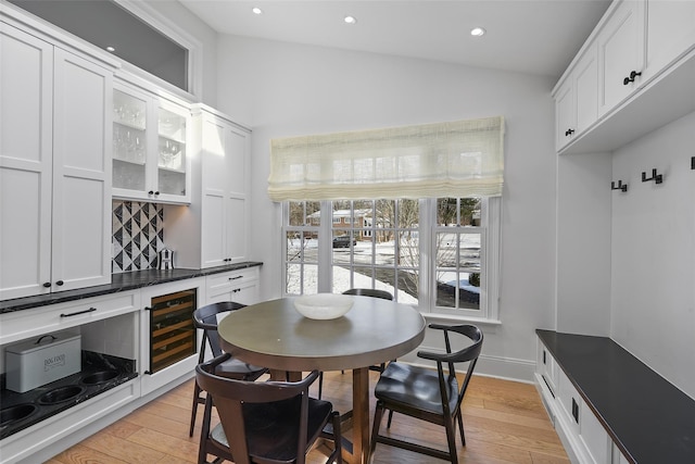 dining area with indoor bar, beverage cooler, and light hardwood / wood-style floors