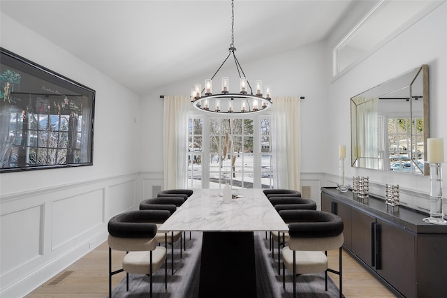 dining area featuring an inviting chandelier, light hardwood / wood-style flooring, and vaulted ceiling