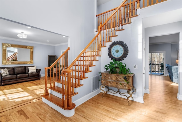 stairs featuring wood-type flooring and ornamental molding