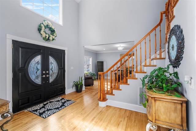 foyer entrance with french doors, ornamental molding, and hardwood / wood-style floors