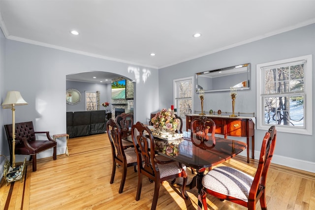 dining space featuring crown molding, a fireplace, and light wood-type flooring