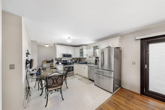 kitchen with sink, stainless steel appliances, white cabinets, and light wood-type flooring