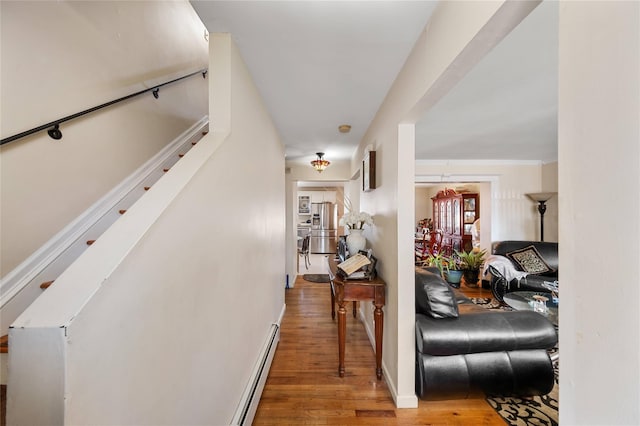 hallway with a baseboard heating unit and hardwood / wood-style floors