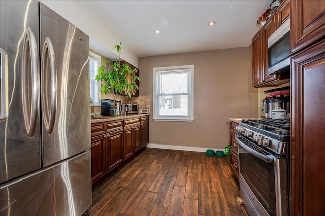 kitchen with light stone countertops, appliances with stainless steel finishes, and dark hardwood / wood-style flooring