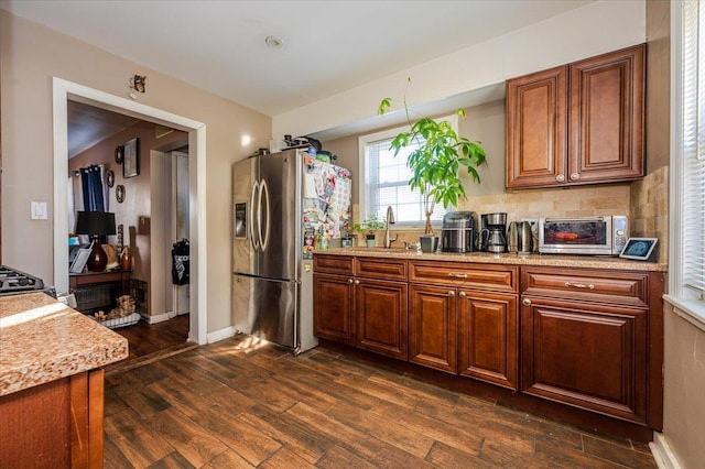 kitchen with stainless steel refrigerator with ice dispenser, decorative backsplash, sink, dark hardwood / wood-style floors, and light stone counters