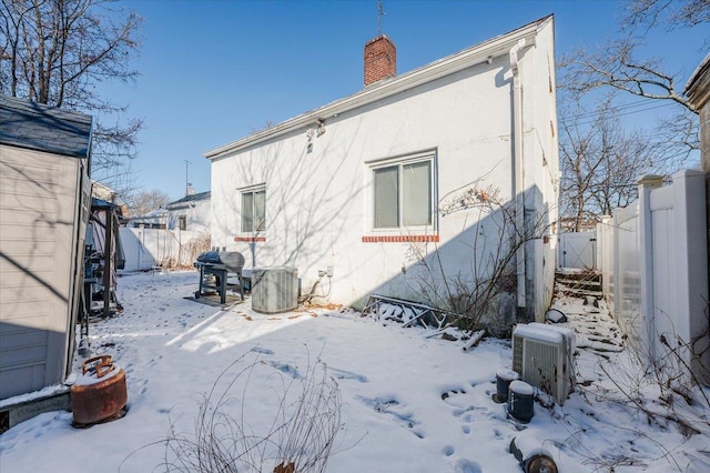 snow covered rear of property with central AC unit