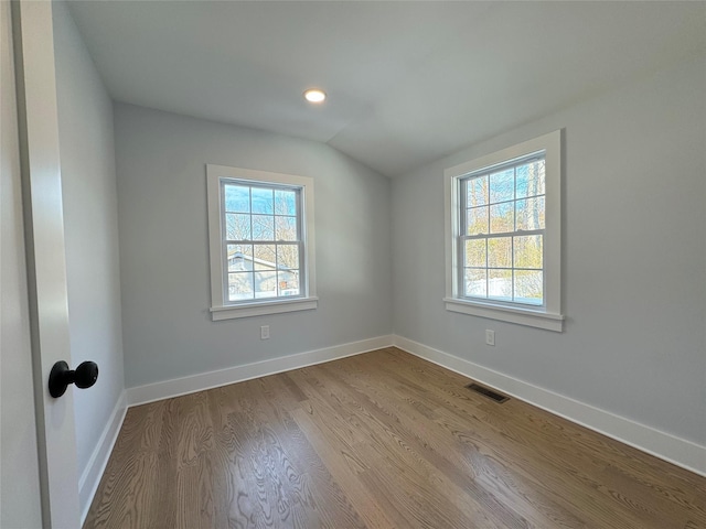 spare room with a healthy amount of sunlight, light hardwood / wood-style flooring, and vaulted ceiling