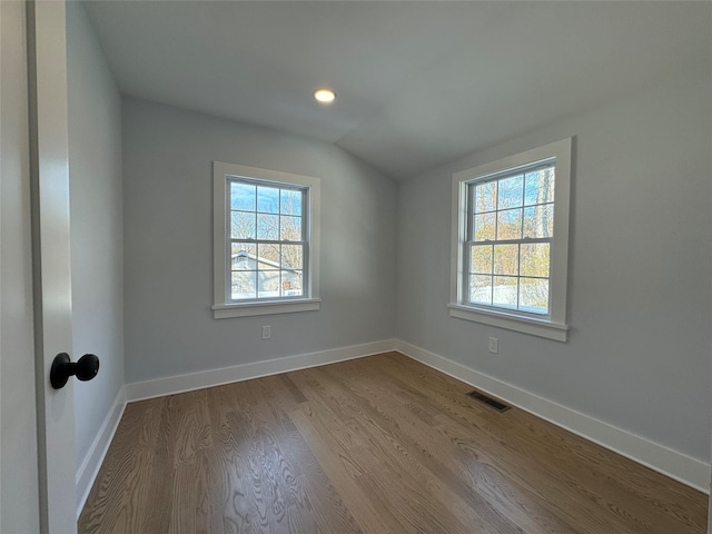 unfurnished room with plenty of natural light, vaulted ceiling, and light hardwood / wood-style floors