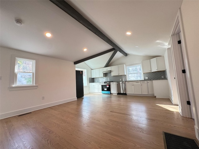 unfurnished living room with light wood-type flooring, lofted ceiling with beams, and a healthy amount of sunlight