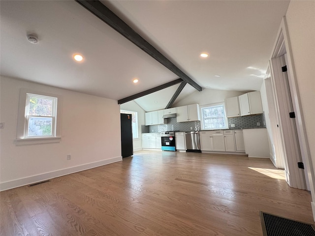 kitchen featuring white cabinets, lofted ceiling with beams, plenty of natural light, and appliances with stainless steel finishes