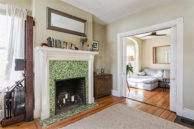 living area featuring hardwood / wood-style flooring, ceiling fan, and a fireplace