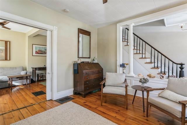 sitting room with decorative columns, hardwood / wood-style floors, and ceiling fan