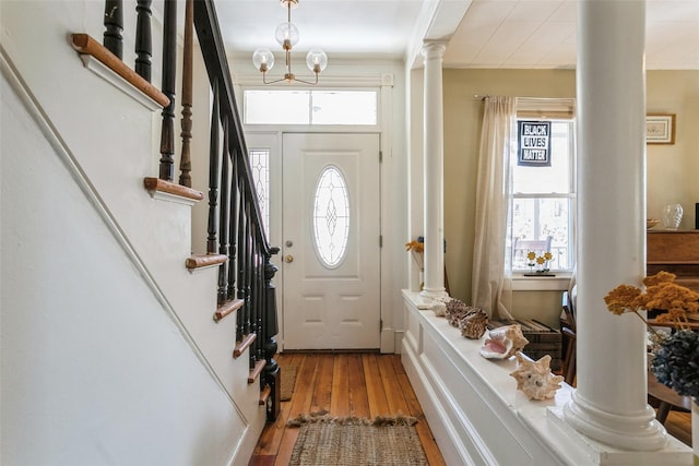 foyer entrance with wood-type flooring, decorative columns, and a healthy amount of sunlight