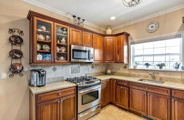 kitchen featuring sink, light stone counters, ornamental molding, stainless steel appliances, and decorative backsplash