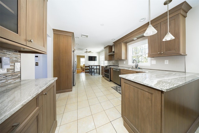 kitchen featuring visible vents, glass insert cabinets, light stone counters, hanging light fixtures, and a sink