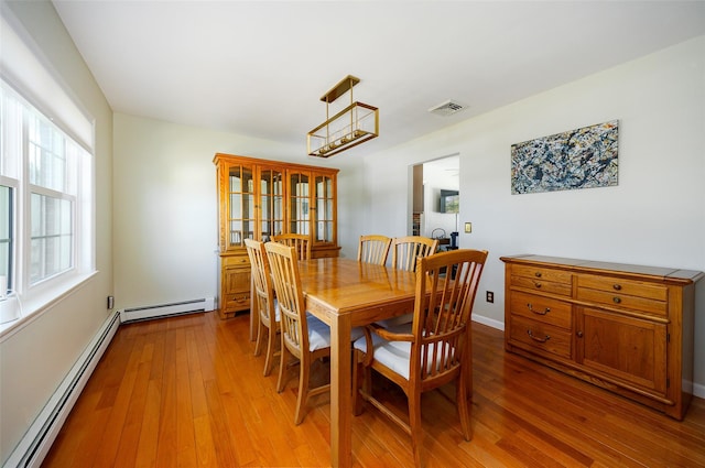 dining space with light wood-style flooring, visible vents, baseboard heating, and baseboards