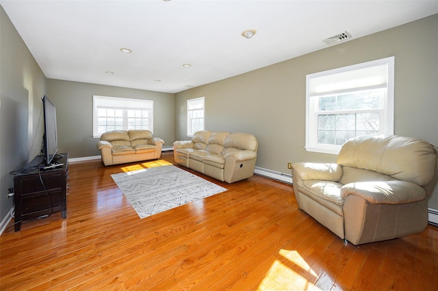 living room with baseboards, visible vents, a baseboard heating unit, and wood finished floors