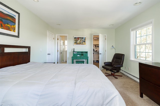 bedroom with a walk in closet, recessed lighting, light colored carpet, a baseboard heating unit, and ensuite bath