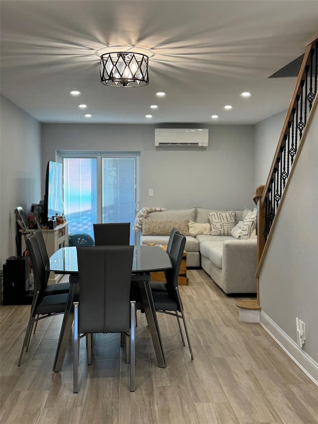 dining area with a wall unit AC and light wood-type flooring