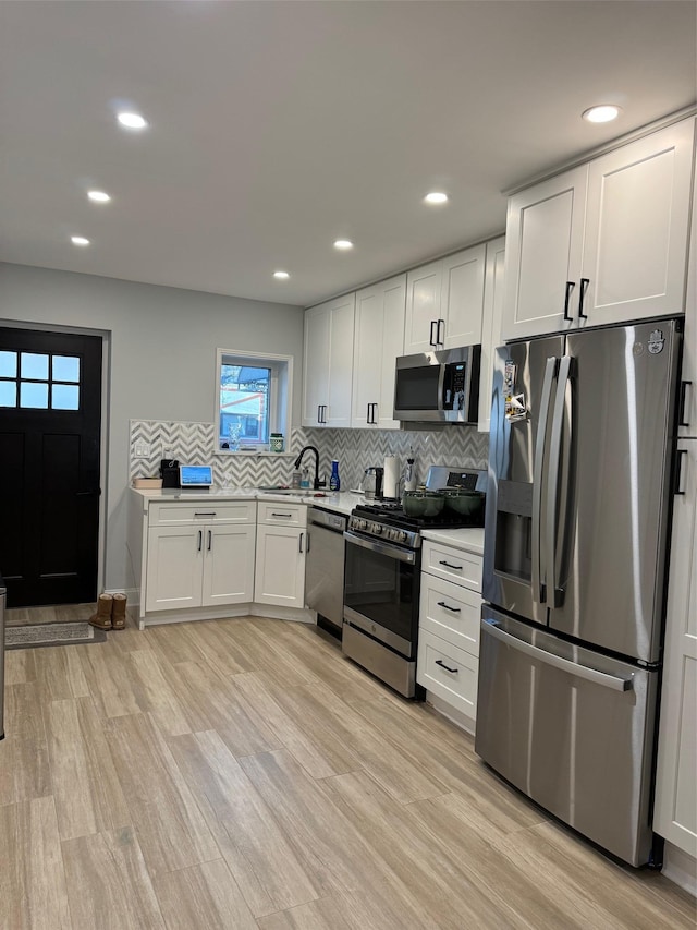 kitchen with tasteful backsplash, appliances with stainless steel finishes, sink, and white cabinets