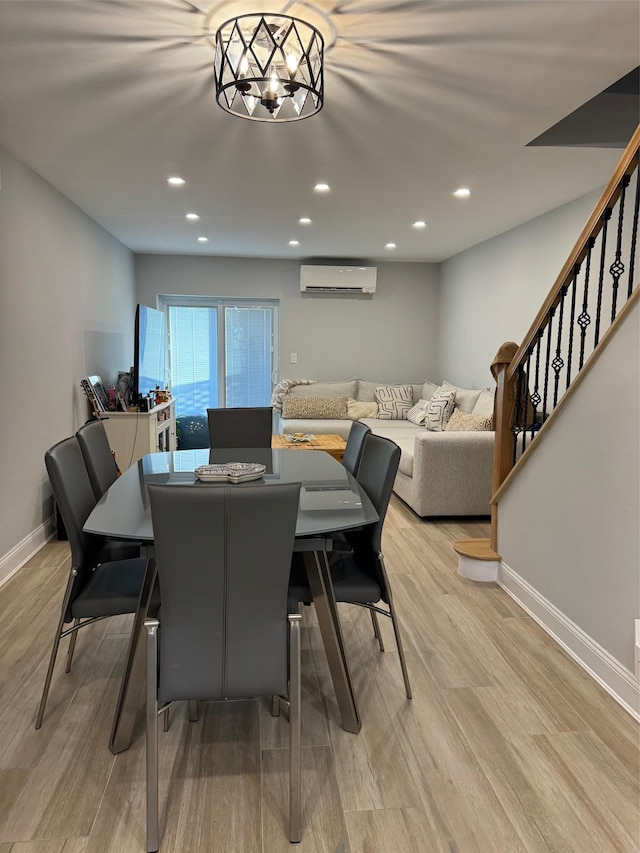 dining room with a wall mounted AC and light hardwood / wood-style flooring