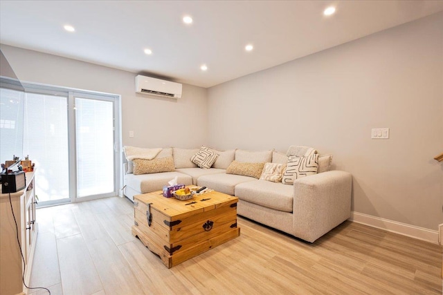 living room with a wall mounted air conditioner and light hardwood / wood-style flooring