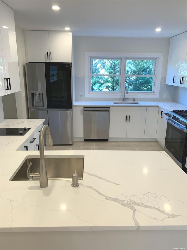 kitchen featuring light stone counters, stainless steel appliances, sink, and white cabinets