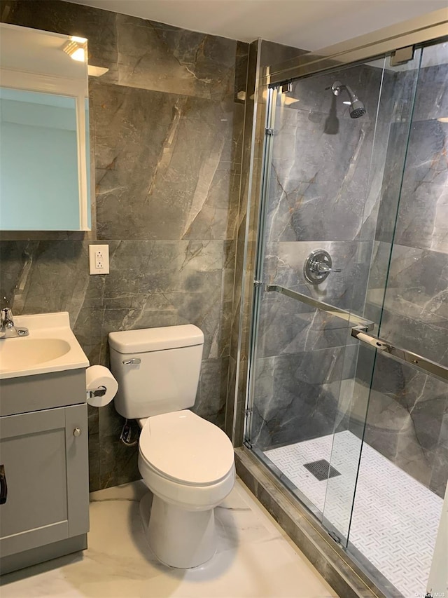 bathroom featuring tile walls, vanity, a shower with door, and toilet