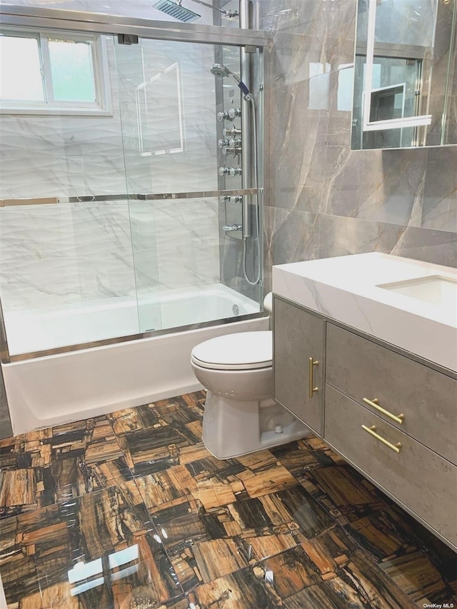 full bathroom featuring enclosed tub / shower combo, vanity, toilet, and tile walls