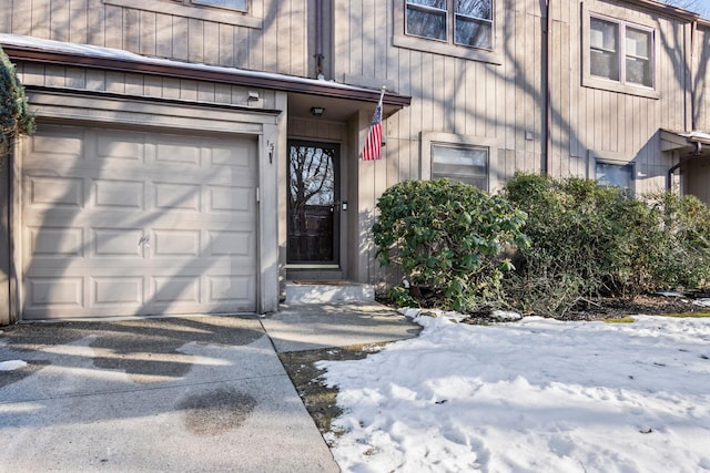 snow covered property entrance with a garage