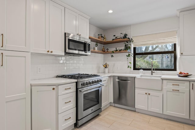 kitchen with white cabinetry, stainless steel appliances, sink, and backsplash