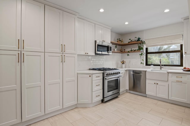 kitchen featuring stainless steel appliances, sink, white cabinets, and decorative backsplash