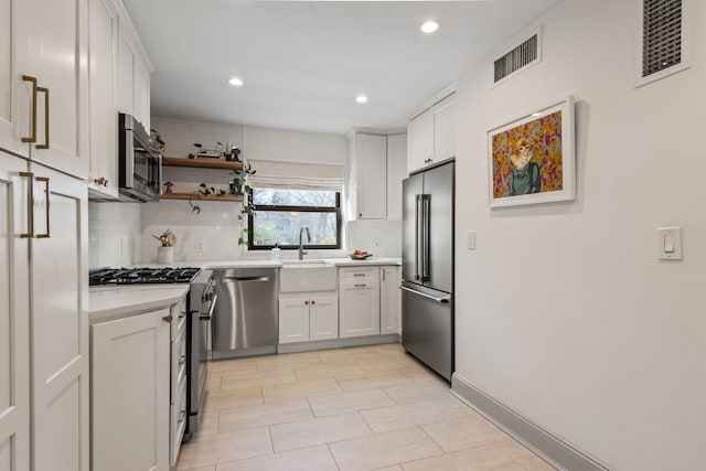 kitchen featuring sink, decorative backsplash, white cabinets, and appliances with stainless steel finishes