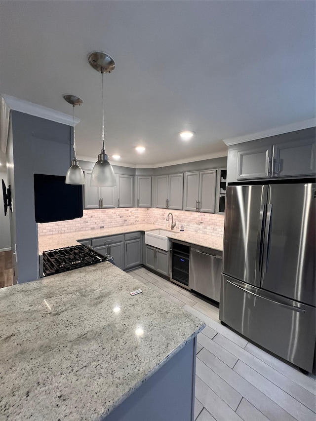 kitchen featuring pendant lighting, appliances with stainless steel finishes, light stone countertops, and sink