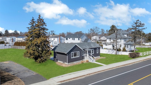 view of front of home with entry steps, a front yard, fence, and a residential view