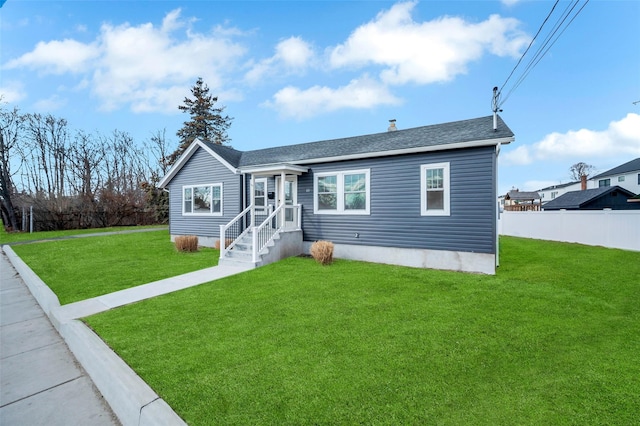 view of front of house featuring a front lawn, roof with shingles, and fence