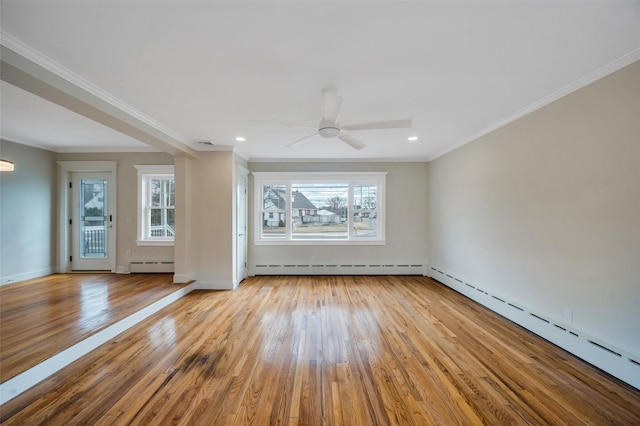 unfurnished room featuring a wealth of natural light, baseboard heating, and wood finished floors