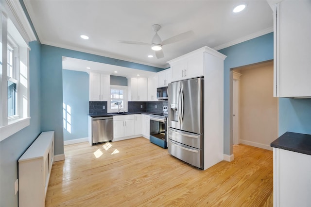 kitchen with light wood finished floors, ornamental molding, and stainless steel appliances